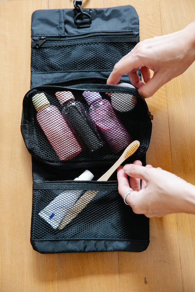 trousse de toilette pliable noire avec des produits rangés